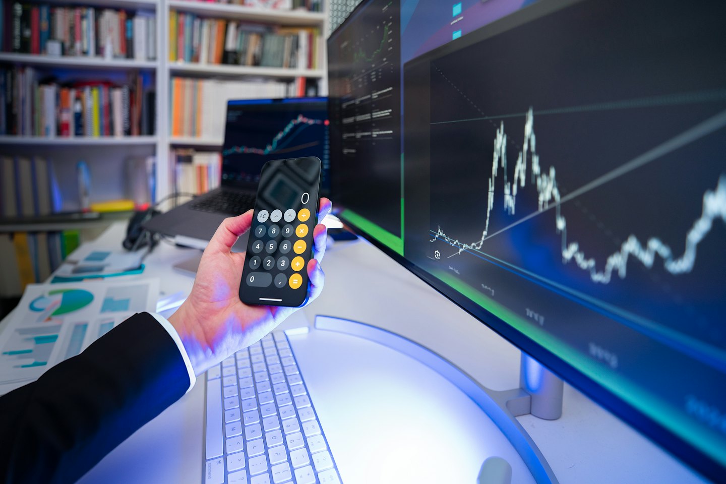 Person analyzes finances using smartphone and computer.